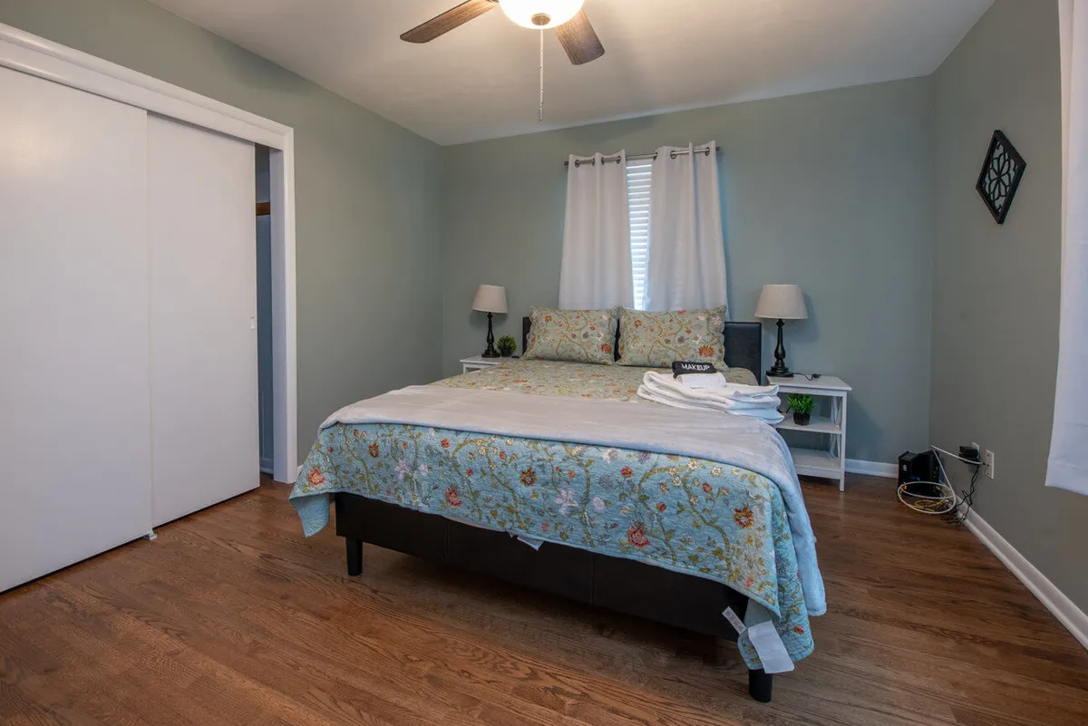 A bedroom scene featuring a bed adorned with floral bedding, nightstands topped with lamps, and warmly-toned wooden flooring. The gentle glow from the lamps and soft, coordinated colors create an intimate, serene environment ideal for unwinding, reading, or savoring peaceful moments.